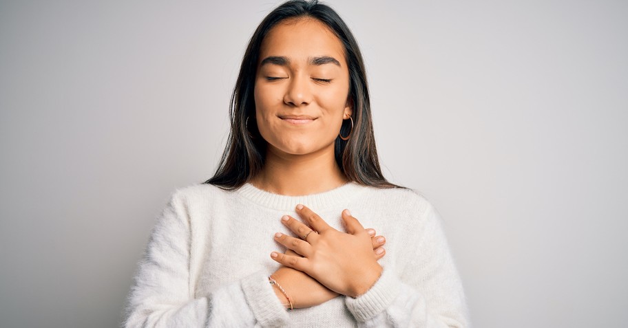 thankful woman smiling with eyes closed and prayer hands over heart