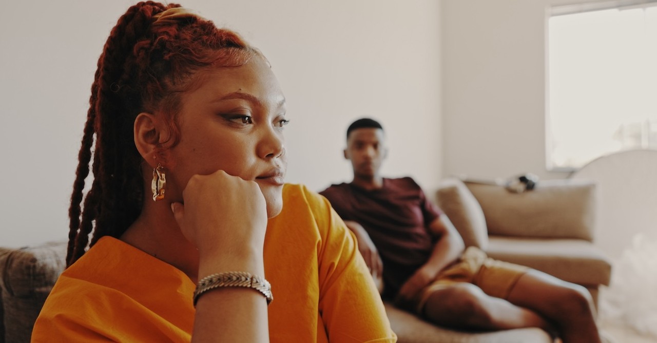Sad serious couple arguing sitting far apart on couch