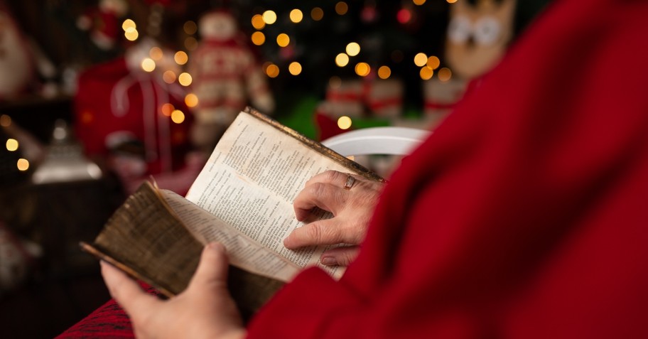 person reading bible with blurred christmas lights in background; christmas prayer bible